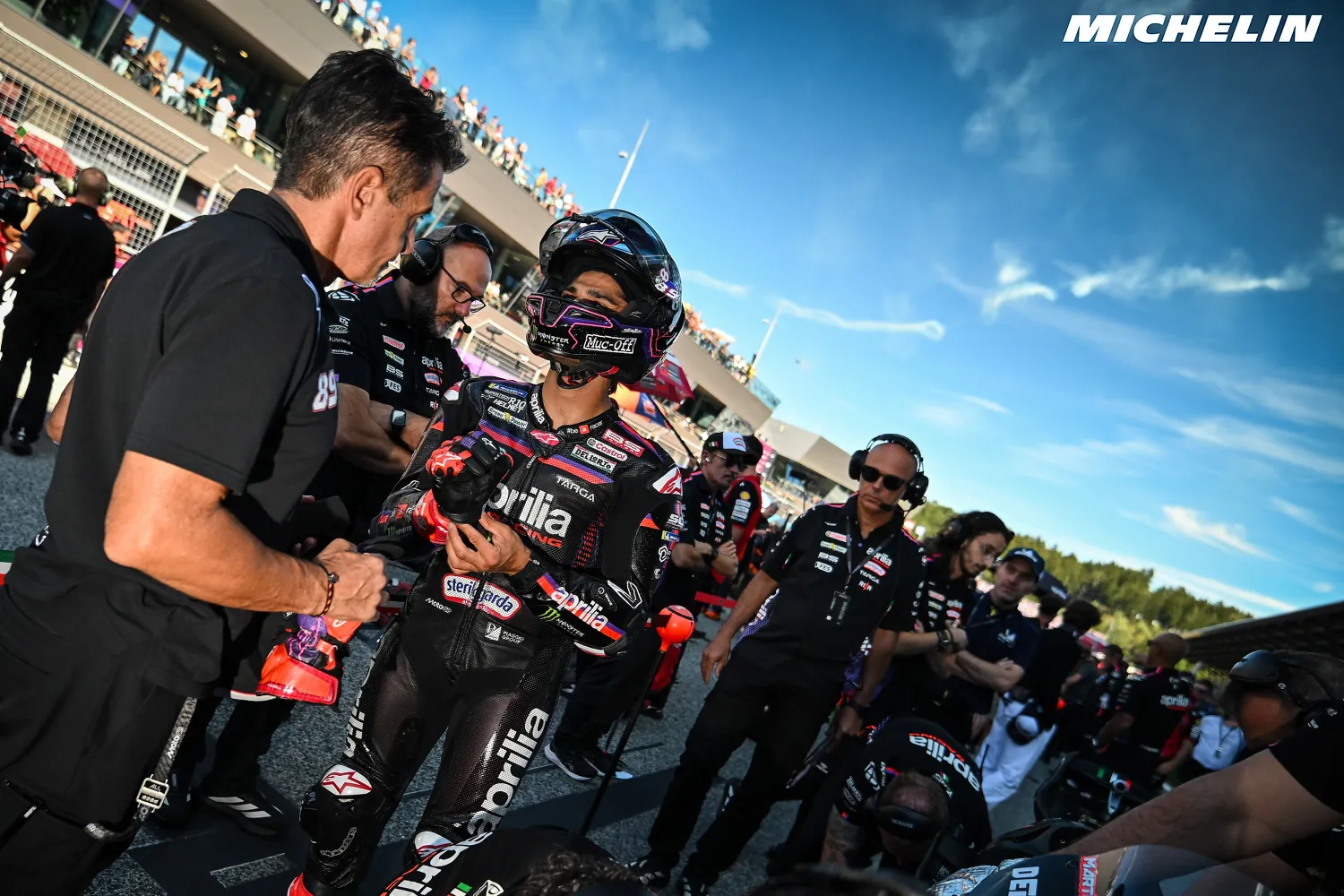 Jorge Martín, casqué, ajuste ses gants au milieu de son équipe Aprilia sur la grille
