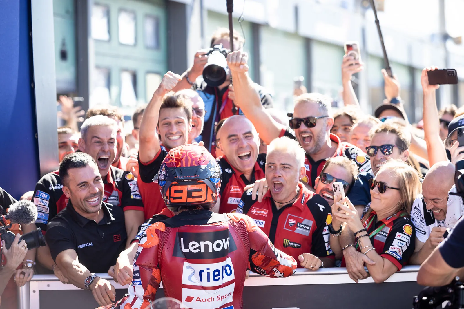 Marc Márquez, casque au numéro 93, fête sa victoire avec son équipe Ducati derrière la barrière