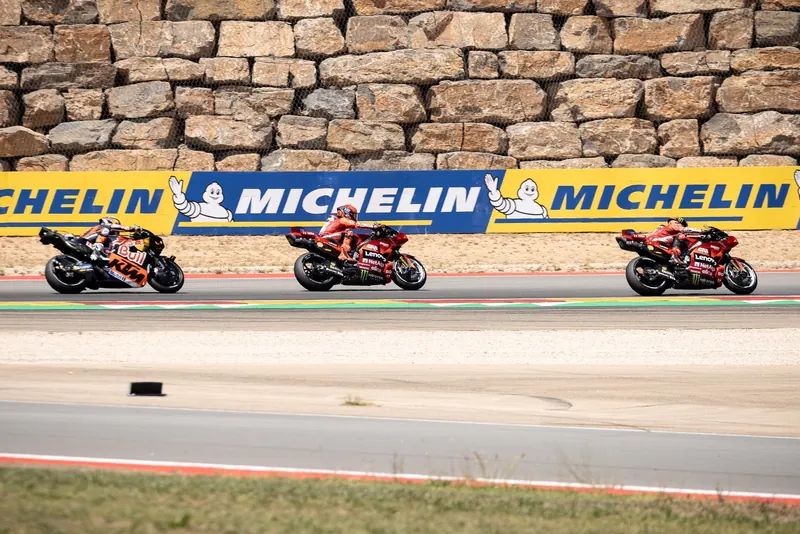 Trois MotoGP en file le long d’un panneau Michelin à MotorLand Aragón