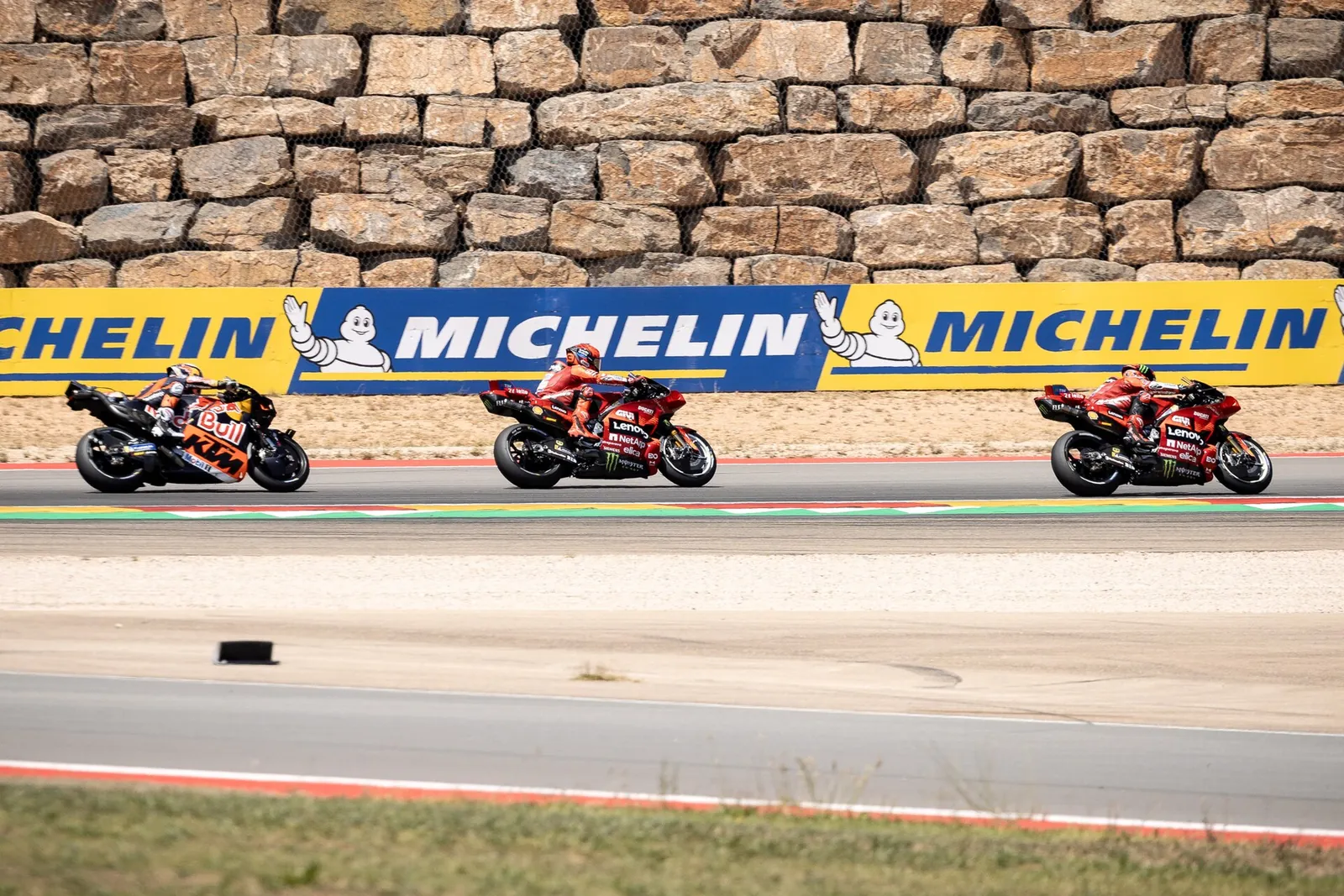 Trois MotoGP en file le long d’un panneau Michelin à MotorLand Aragón
